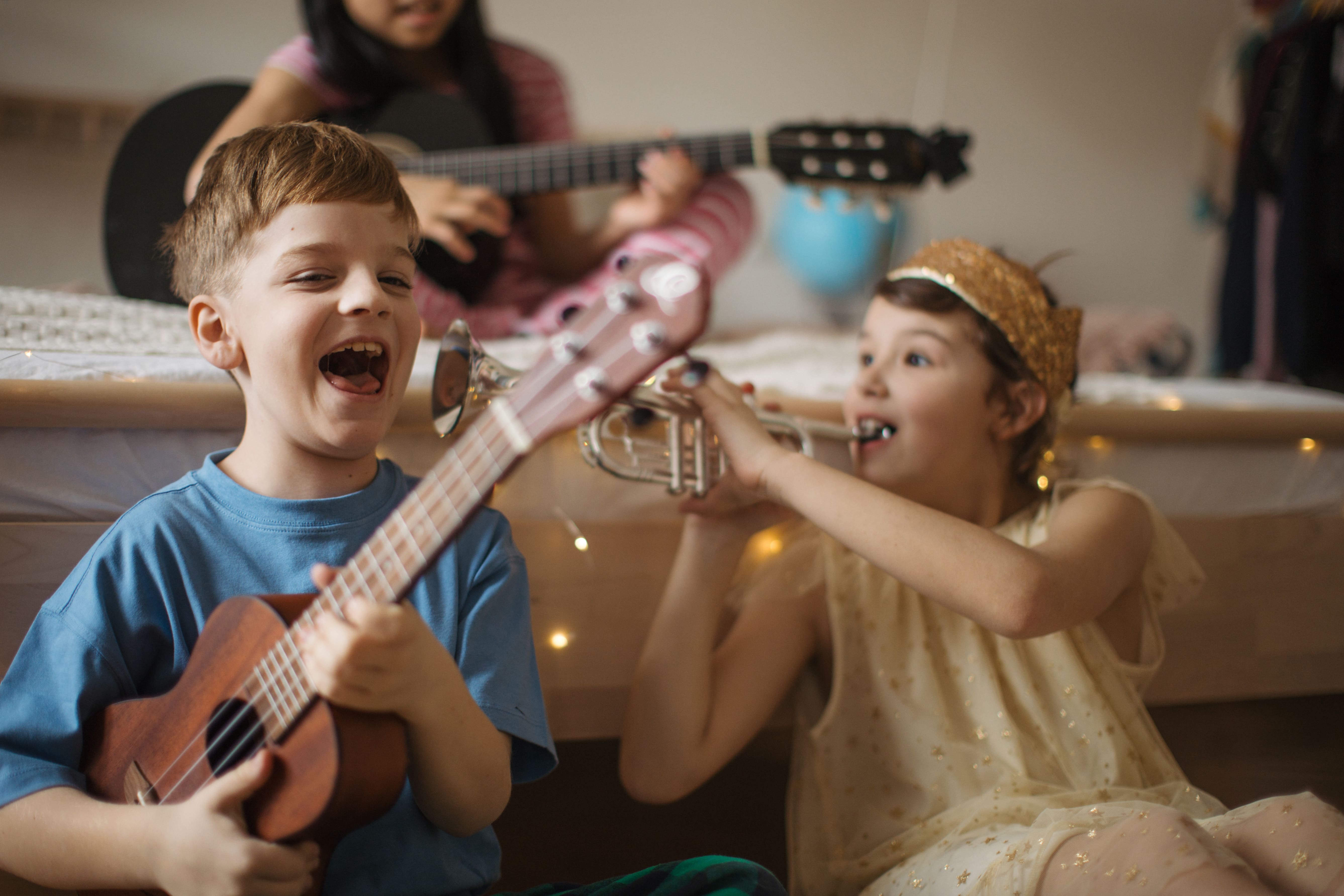 Two children laughing and having fun playing musical instruments. 